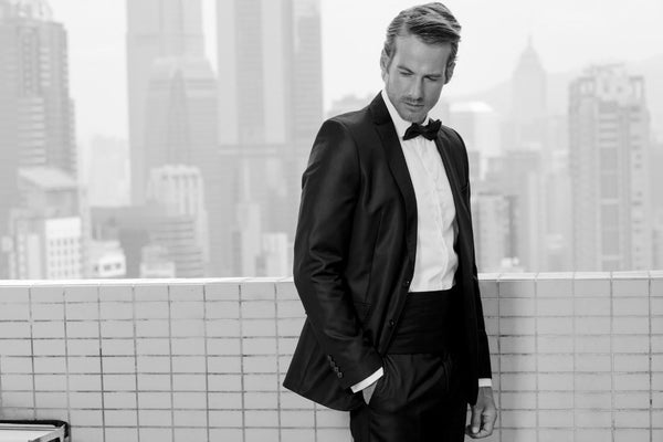 Man in a black tuxedo standing near a balcony