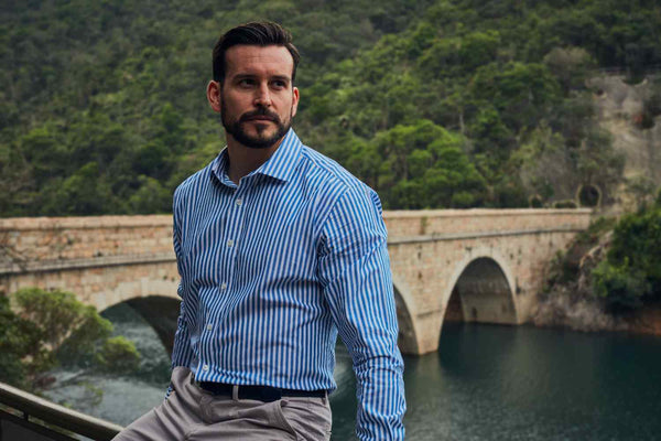 Man wearing a blue and white striped dress shirt standing outdoors